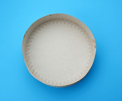 empty cardboard round cover for packing a cake on a blue background, top view