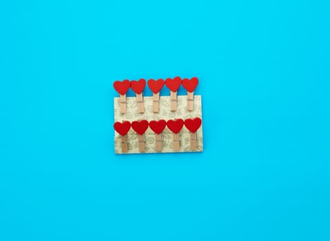 wooden decorative clothespins on a blue background with red hearts, top view
