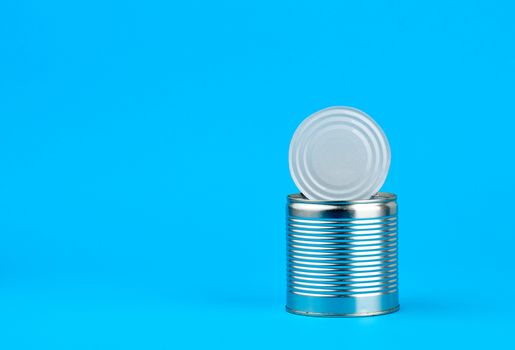 open hard iron can for food preservation on a blue background, copy space