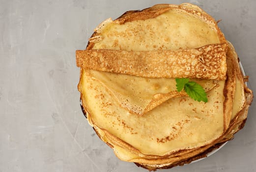 stack of fried round pancakes on a plate, gray background, top view, copy space