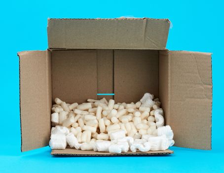 open rectangular brown cardboard box with white foam filling for transporting goods on a blue background
