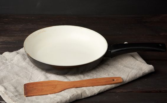 round iron empty pan and wooden spatula on the table, kitchen utensils