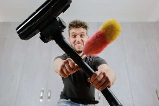 A man with a dust brush and a vacuum cleaner. House cleaning.