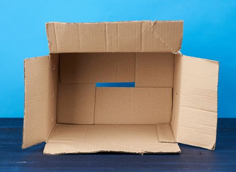 open empty brown rectangular cardboard box for transporting goods on blue wooden background