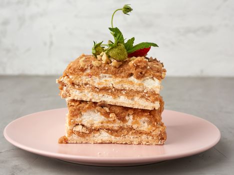 square pieces of meringue cake with cream on a pink plate , close up
