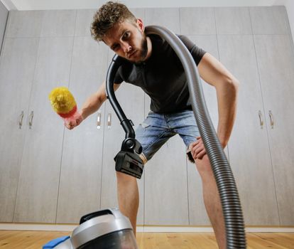 A man with a dust brush and a vacuum cleaner. House cleaning.