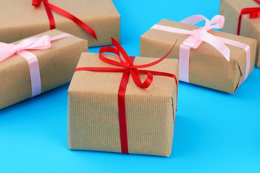 boxes wrapped in brown paper and tied with a silk ribbon, gifts on a blue background, top view. Festive concept