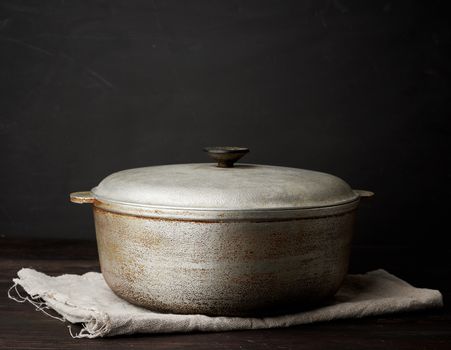 aluminum old cauldron on a wooden table, kitchen utensils