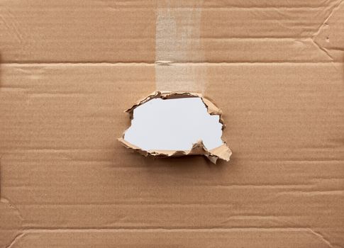 hole in brown cardboard paper with torn and curved edges. Blank template.