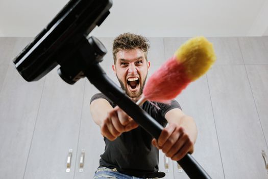 A man with a dust brush and a vacuum cleaner. House cleaning.