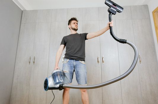 House cleaning. Man with a vacuum cleaner