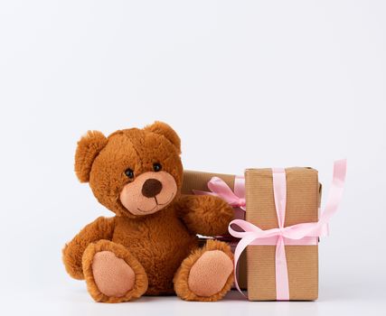 brown teddy bear, stack of gifts in boxes wrapped in brown paper, tied with silk ribbon, happy birthday and valentines da