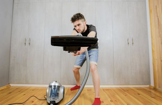 House cleaning. Man with a vacuum cleaner