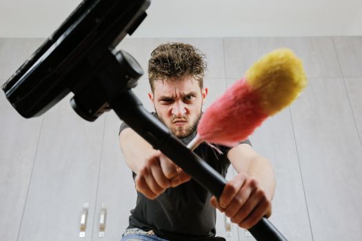 A man with a dust brush and a vacuum cleaner. House cleaning.