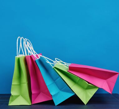 multicolored paper bags with a handle for shopping and gifts on a blue background