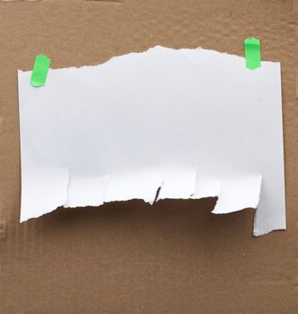 blank paper ad with torn edges attached with a green velcro on a brown cardboard surface, backdrop for sales and messages, copy space