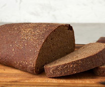 sliced oval rye bread bread on a wooden board, close up