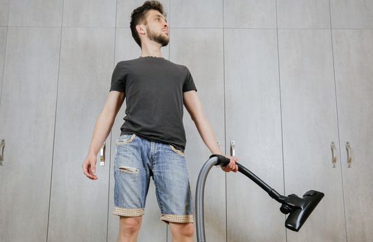 House cleaning. Man with a vacuum cleaner