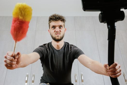 A man with a dust brush and a vacuum cleaner. House cleaning.