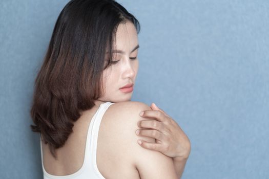 Woman hand scratching her shoulder with grey background, health care and medical concept