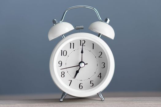 Alarm clock on wooden table with grey background, selective