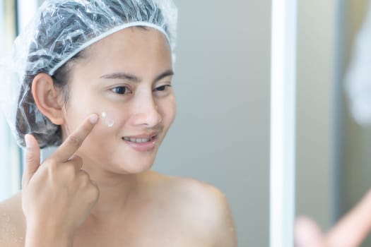 Woman hand applying cream on her face with happy feeling, health care and beauty concept