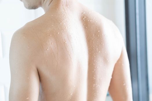 Closeup back of handsome asian man taking a shower in the bathroom, selective focus