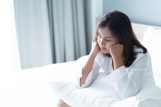 Closeup woman sitting on bed in the bedroom with thinking or depressed feeling, selective focus