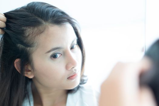 Woman looking reflection in the mirror serious hair loss problem for health care shampoo and beauty product concept