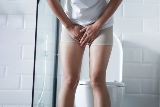 Close up woman stomachache with toilet in the morning, health care concept, selective focus