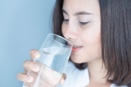 Close up woman drinking pure water from glass with light in the morning, Selective focus