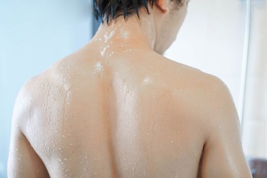 Closeup handsome asian man taking a shower in the bathroom, selective focus