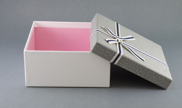 Grey gift box with ribbon on grey background, copy space