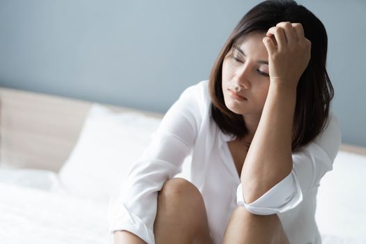 Closeup woman sitting on bed in the bedroom with thinking or depressed feeling, selective focus