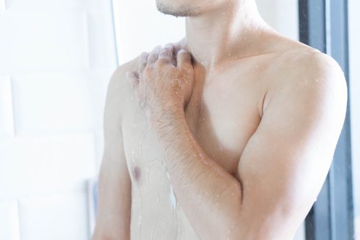 Closeup handsome asian man taking a shower in the bathroom, selective focus