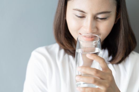 Close up woman drinking pure water from glass with light in the morning, Selective focus