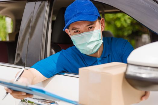 Asian delivery courier young man driver inside van car giving parcel post boxes to customer receiving both protective face mask, under curfew quarantine pandemic coronavirus COVID-19