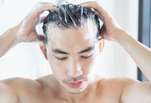 Closeup young man washing hair with with shampoo in the bathroom, vintage tone, selective focus