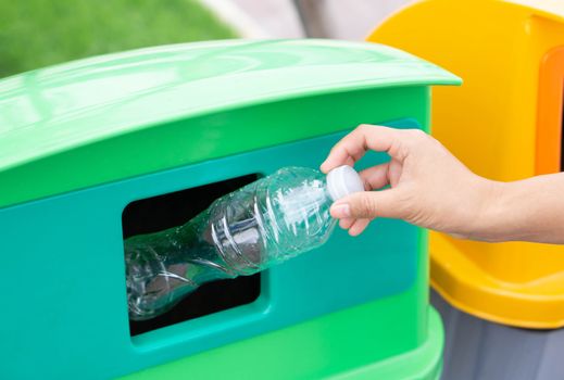 Close up hand holding garbage plastic bottle into recycle trash bin, selective focus