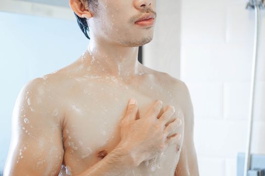 Closeup handsome asian man taking a shower in the bathroom, selective focus