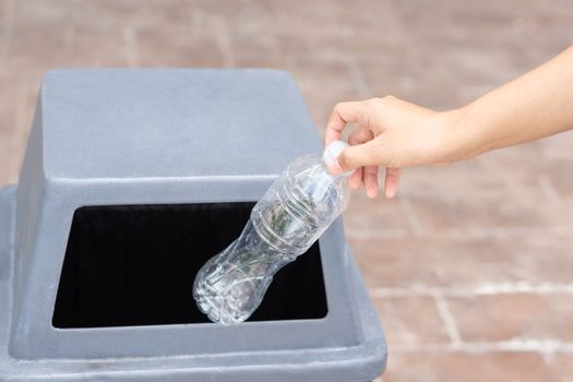 Close up hand holding garbage plastic bottle into recycle trash bin, selective focus