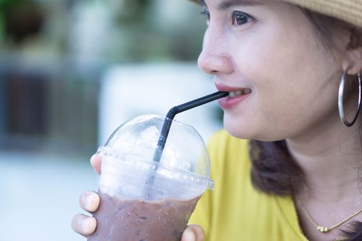 Close up woman drinking ice coffee from glass in the morning