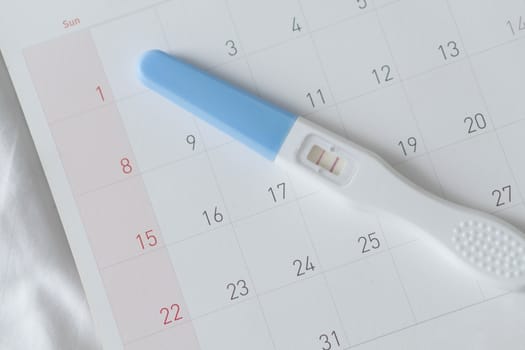 Pregnancy test on calendar background, health care concept
