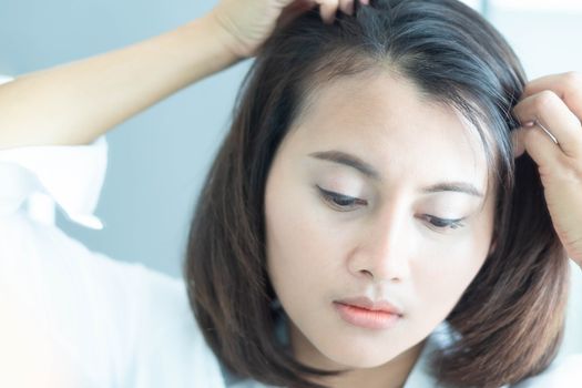 Woman looking reflection in the mirror serious hair loss problem for health care shampoo and beauty product concept