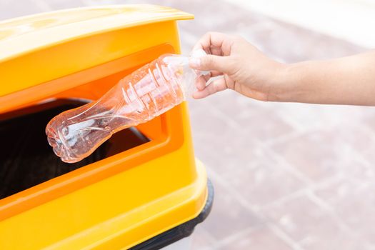 Close up hand holding garbage plastic bottle into recycle trash bin, selective focus