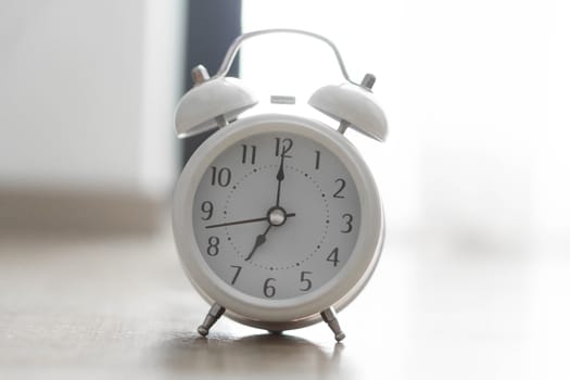Alarm clock on wooden table with grey background, selective