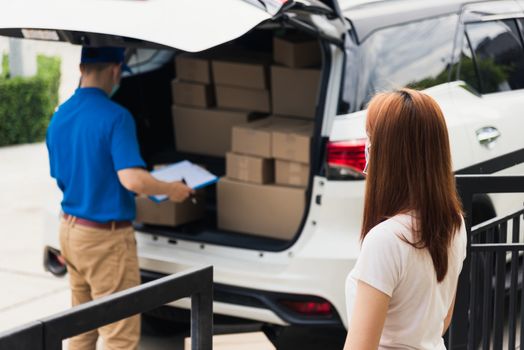 Asian young delivery man courier shopping online give parcel post box he protective face mask and service woman customer receiving boxed at front home door, under curfew pandemic coronavirus COVID-19