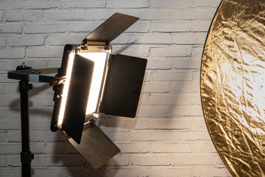 Bright spotlight and gold reflector positioned in front of a binary brick wall in the photo studio