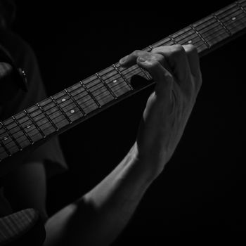 detail of hand playing an electric guitar, black and white image