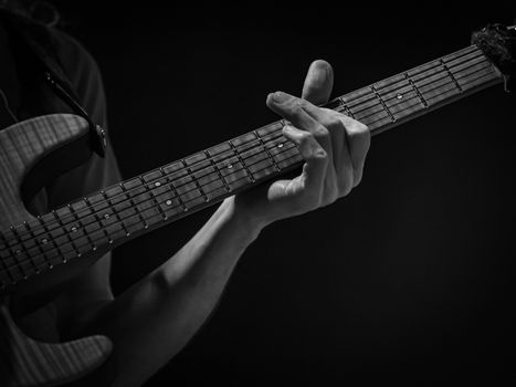 detail of hand playing an electric guitar, black and white image